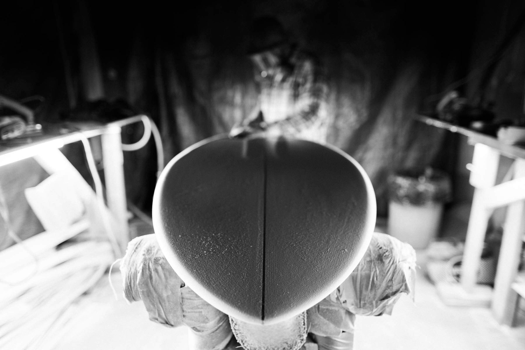 A surfboard blank taking shape under the lights in the shaping bay